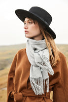 Model in a black hat and brown wrap coat wearing the Quartz light grey scarf outdoors