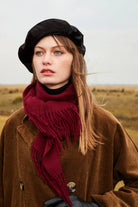 Model in a black beret wearing the Rhubarb burgundy merino scarf over a corduroy coat