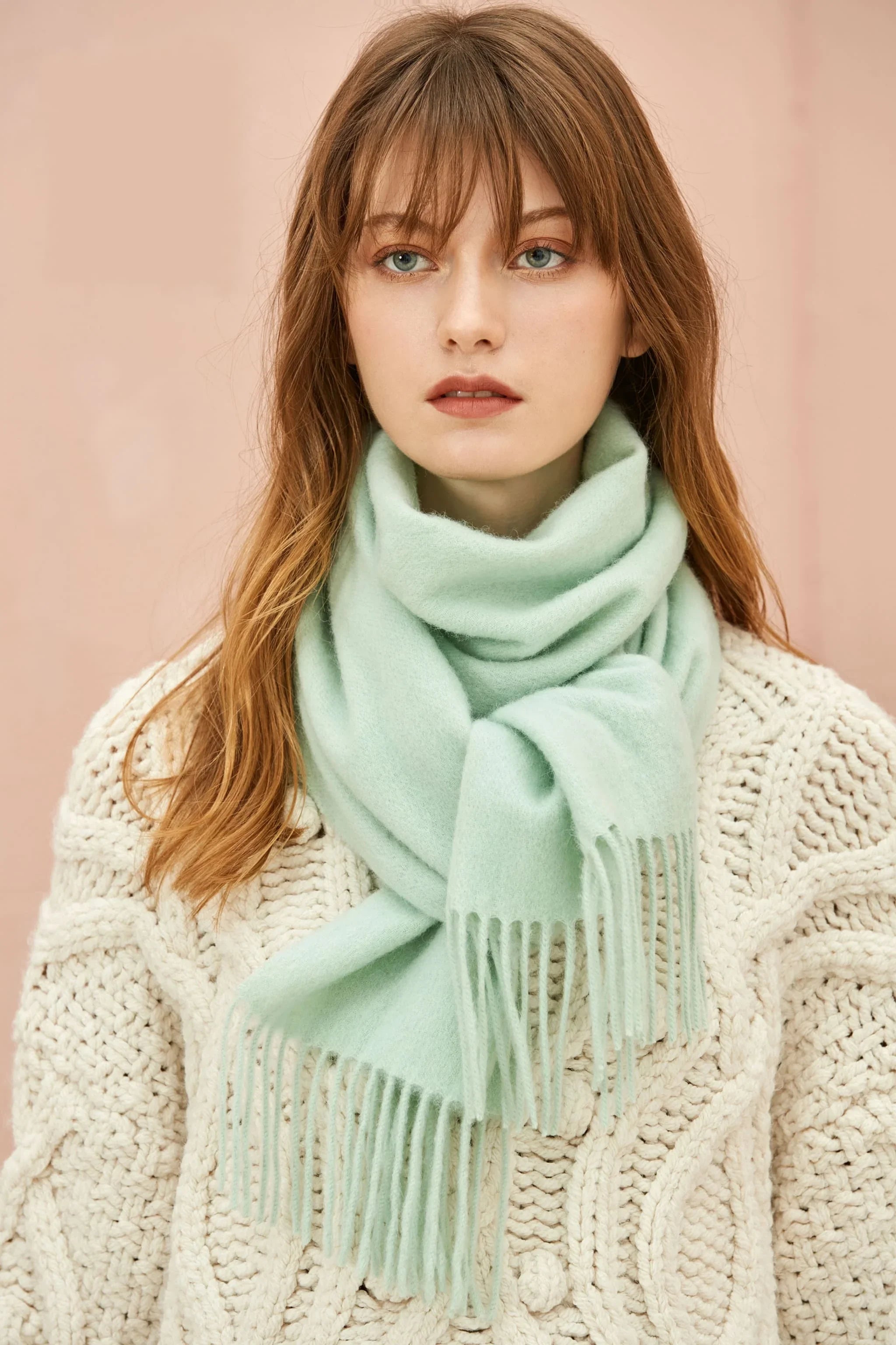 Model in a cream cable knit wearing the Pistachio mint merino scarf