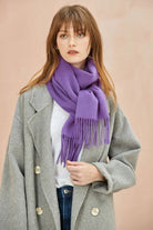 Model in a grey coat wearing the Iris violet merino scarf knotted at the front