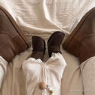Baby lying between two adults wearing chocolate sheepskin booties