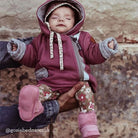 Baby in a plum hooded suit held up wearing orchid pink sheepskin booties