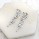 Cubic zirconia leaf-drop clip-on earrings lying flat on marble showing the clip fastening, silver tone