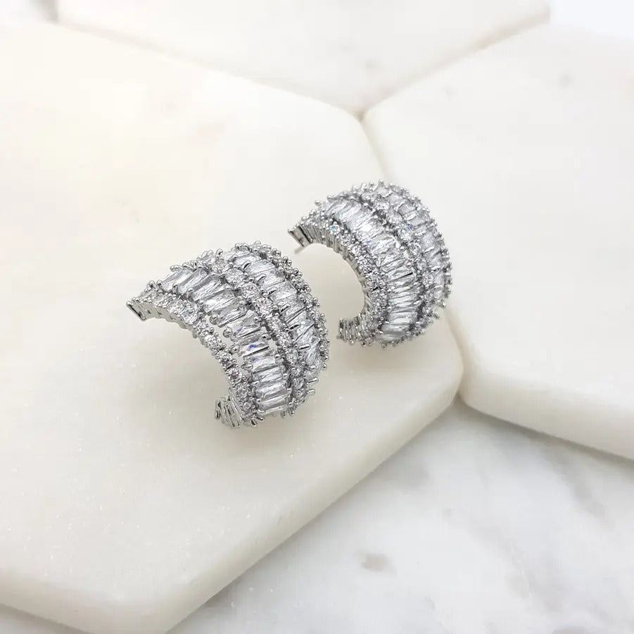 Pair of silver-tone oval cluster earrings set with clear marquise cubic zirconia, on white marble