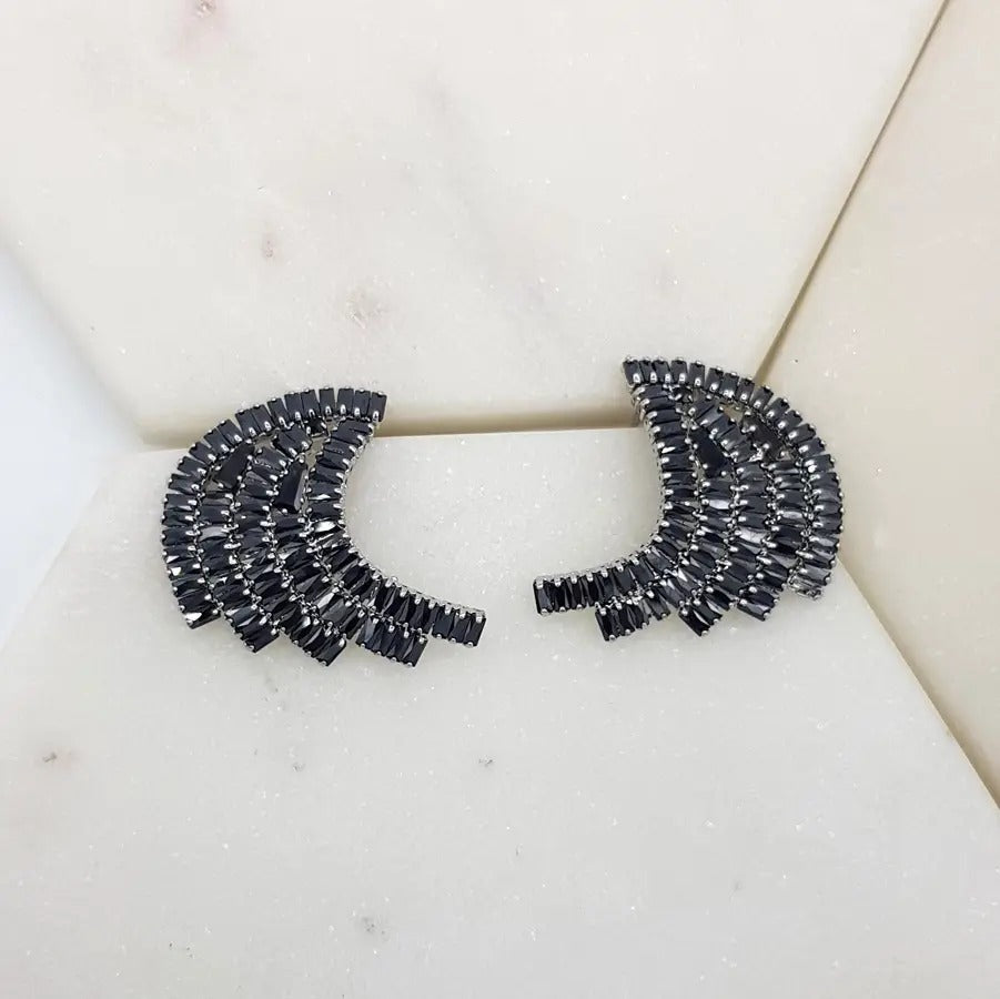 Pair of black cubic zirconia fan-shaped baguette earrings in a rhodium setting on white marble