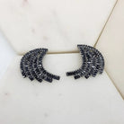 Pair of black cubic zirconia fan-shaped baguette earrings in a rhodium setting on white marble