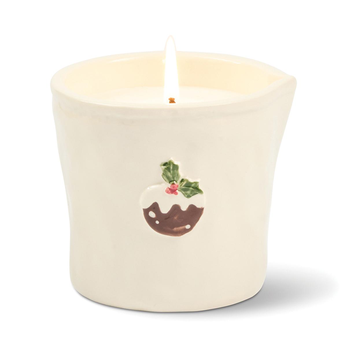 Cream ceramic tumbler candle with a raised Christmas pudding and holly on the front, lit.