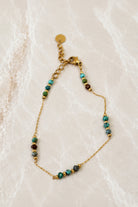 Fine gold chain bracelet with small turquoise and green stone beads grouped along the chain