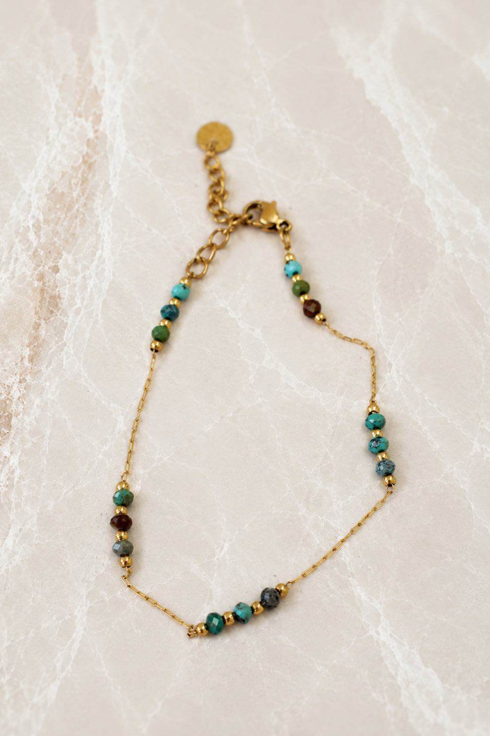 Fine gold chain bracelet with small turquoise and green stone beads grouped along the chain