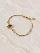 Smooth gold cuff bracelet with an olive-green marquise stone set into the band
