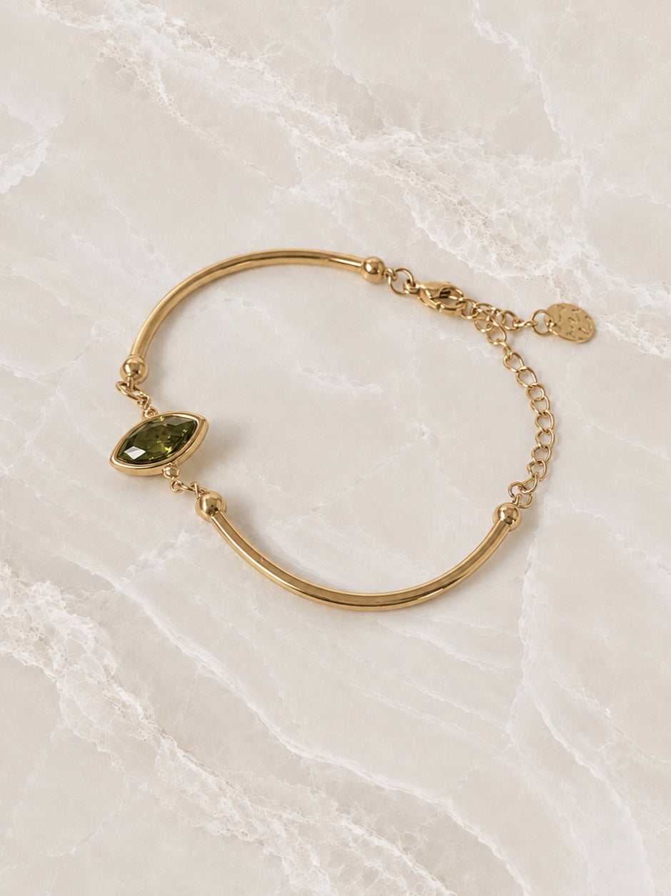 Smooth gold cuff bracelet with an olive-green marquise stone set into the band