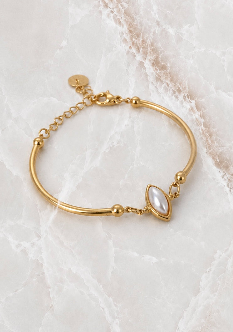 Smooth gold cuff bracelet with a white pearl marquise stone set into the band