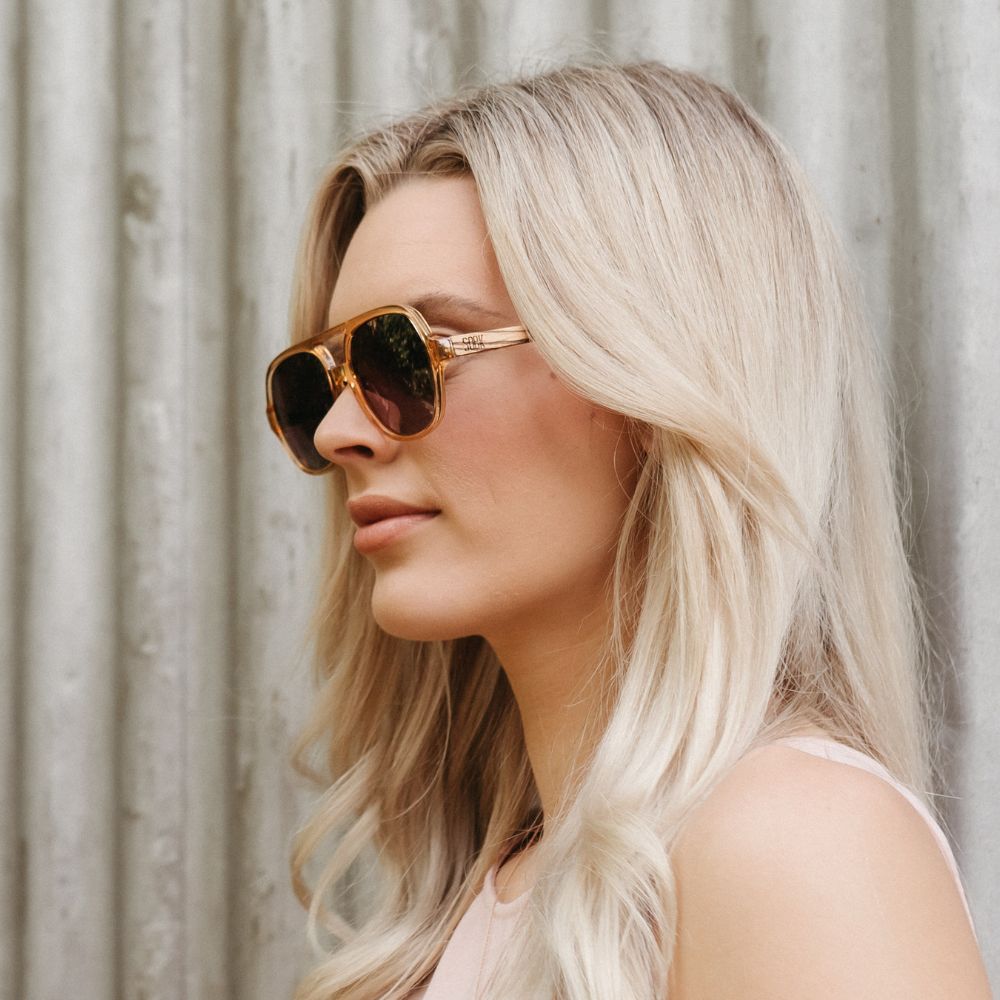 A woman in profile outdoors wearing the Billy sunglasses, showing how they sit on the side of the face