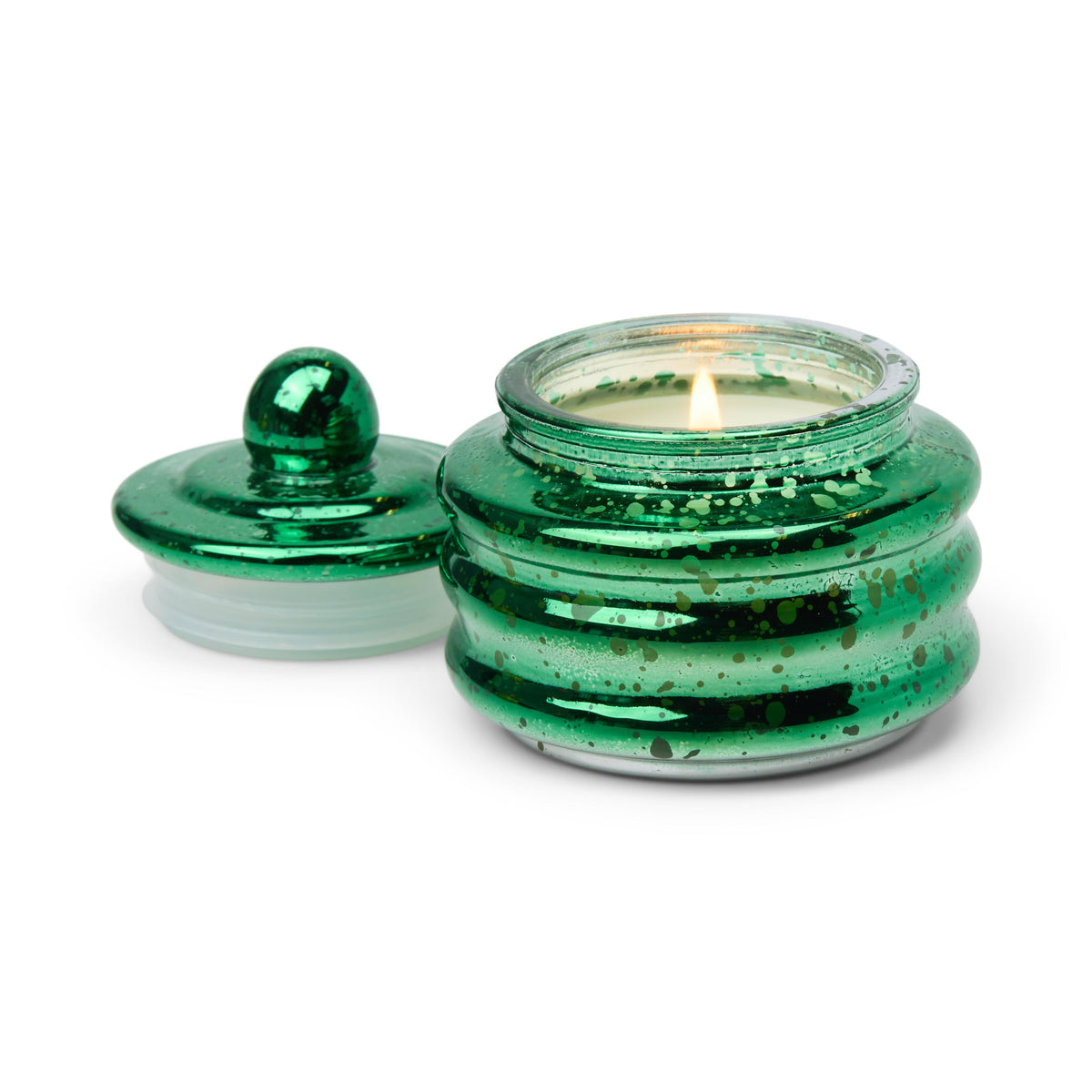 Green mercury glass candle lit, its domed lid set beside it.