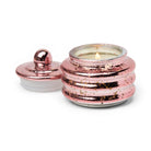 Rose-pink mercury glass candle lit, its domed lid set beside it.