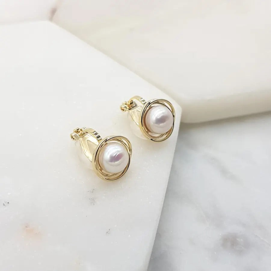 Gold freshwater pearl swirl clip-on earrings angled to show the clip back