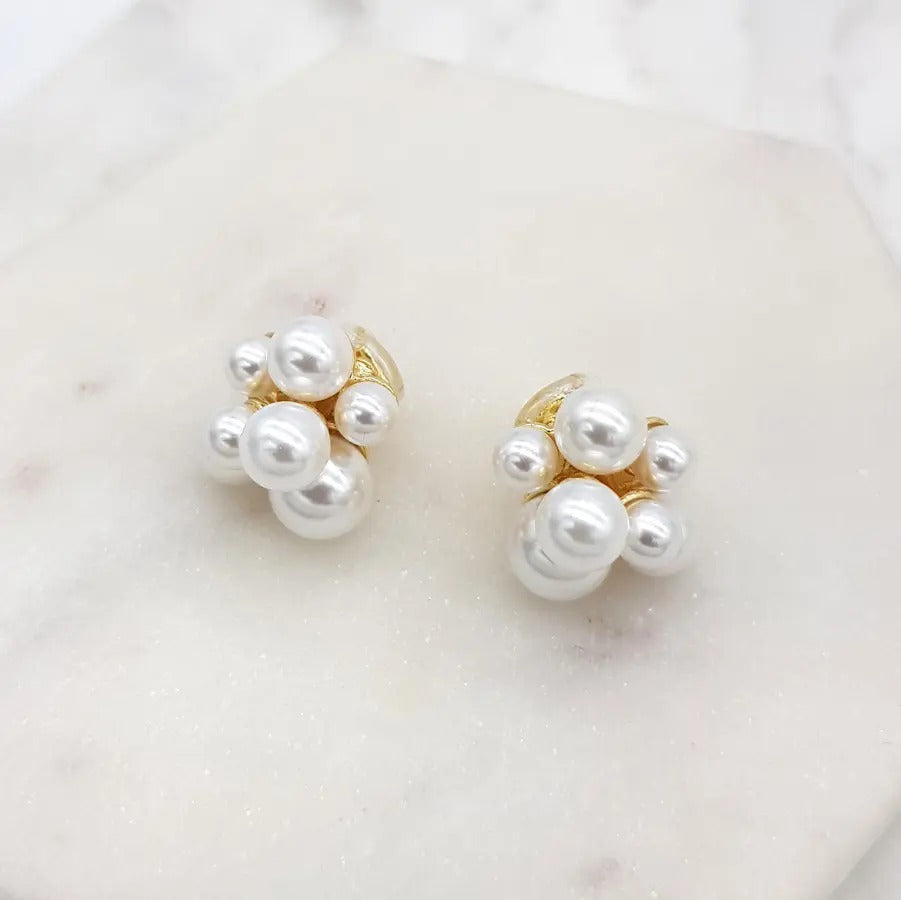 Pearl cluster clip-on earrings close up on a marble tile