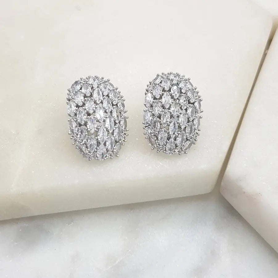 Pair of silver-tone oval clip-on earrings pavé-set with clear cubic zirconia, on white marble