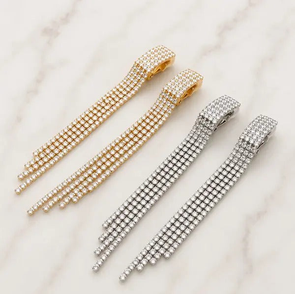 Two pairs of crystal fringe clip-on earrings, gold tone and silver tone, four rows of crystals each, on marble