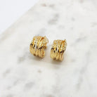 Pair of gold-tone ribbed multi-band hoop clip-on earrings on white marble