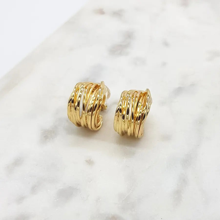 Pair of gold-tone ribbed multi-band hoop clip-on earrings on white marble