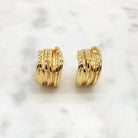 Gold ribbed hoop clip-on earrings close up on marble