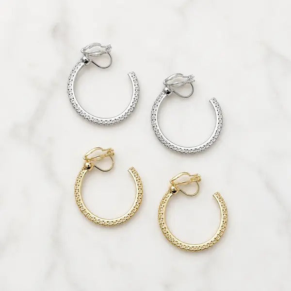 Crystal hoop clip-on earrings in silver and gold, two pairs on a white background