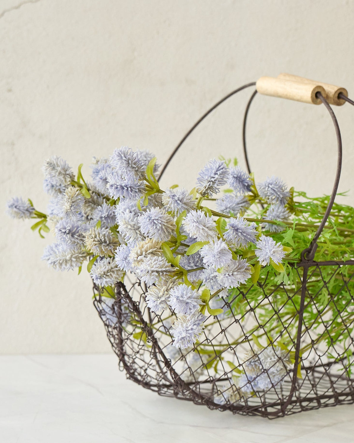 French potager wire basket holding pale blue muscari on a marble bench
