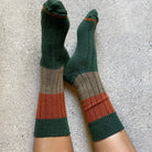 Legs crossed on concrete wearing the green, rust and khaki rib socks