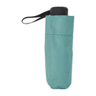 Eucalyptus green folded umbrella standing upright with a black handle and wrist strap.