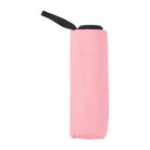 Pale pink folded umbrella standing upright with a black handle and wrist strap.