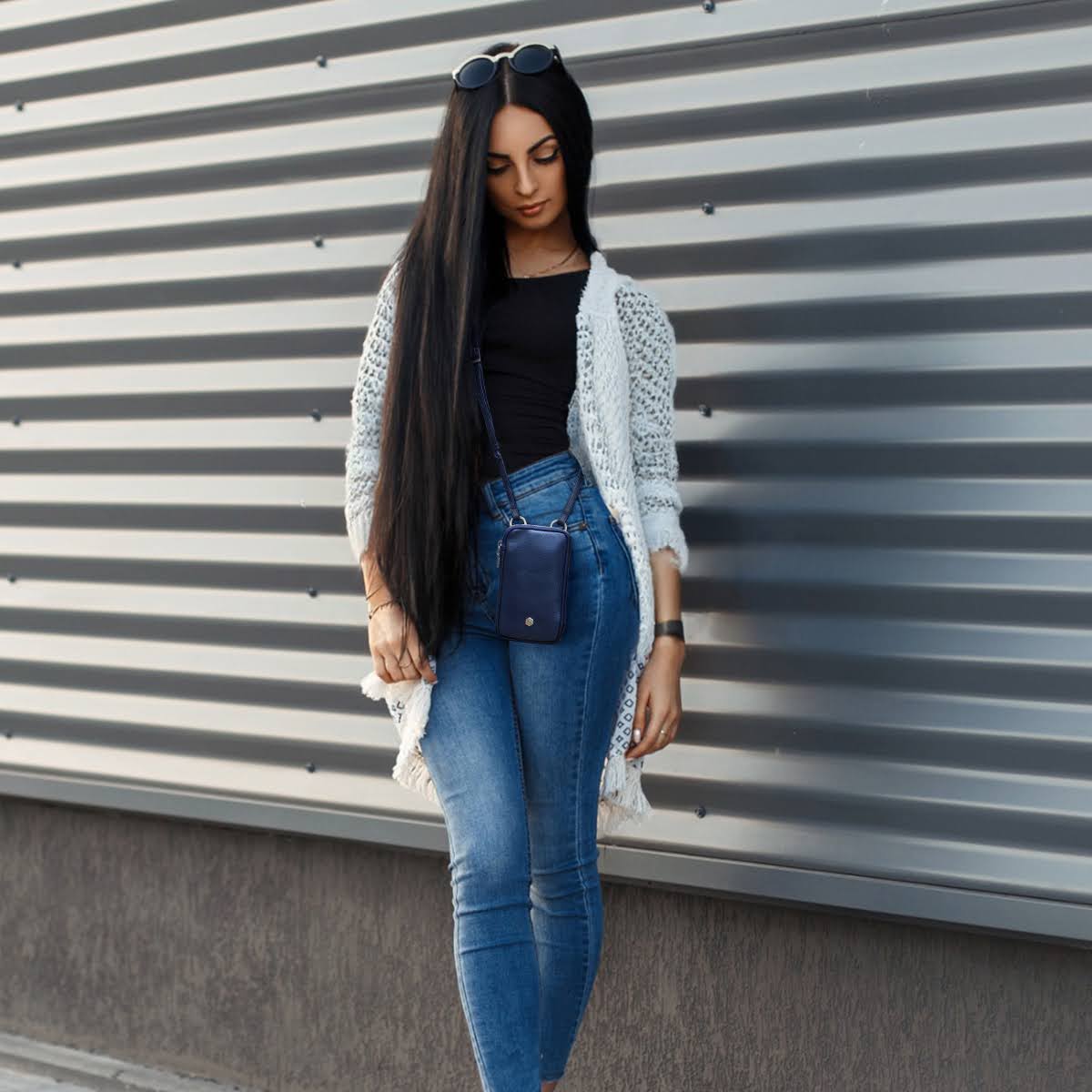 Woman in jeans and a cream cardigan wearing the navy phone pouch crossbody