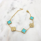 Gold-tone bracelet alternating teal four-leaf clovers with pavé cubic zirconia clovers, with extender chain, on marble