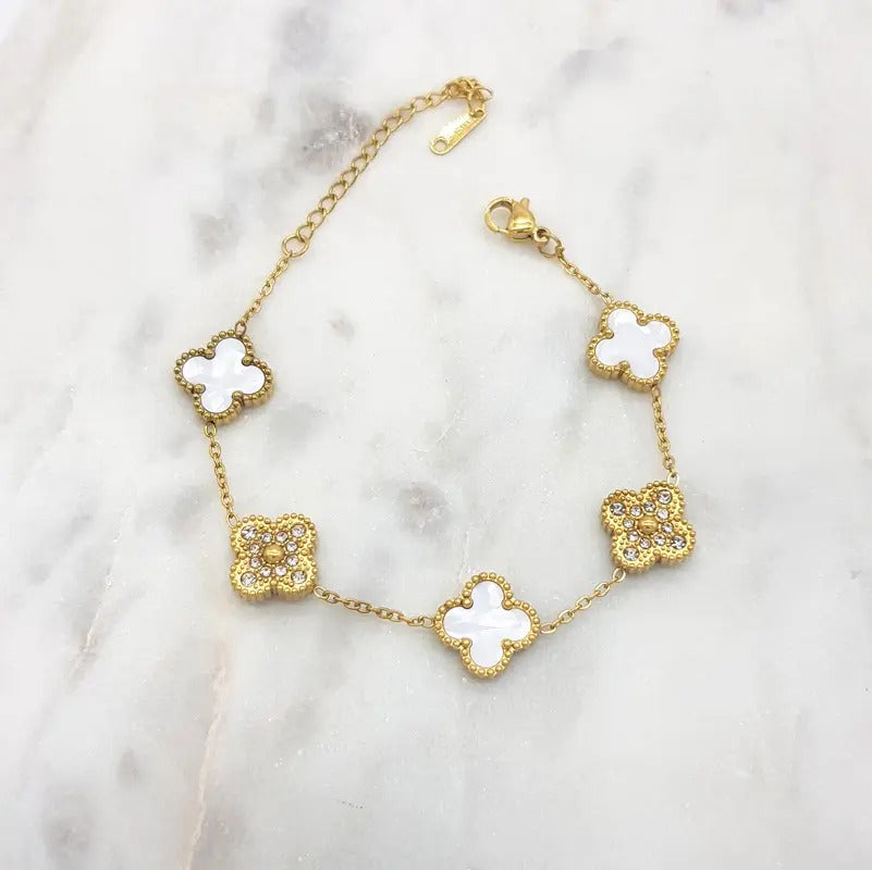 Gold-tone bracelet alternating white four-leaf clovers with pavé cubic zirconia clovers, on marble