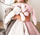 Child hugging grey, white and pink bunny lovey blankets