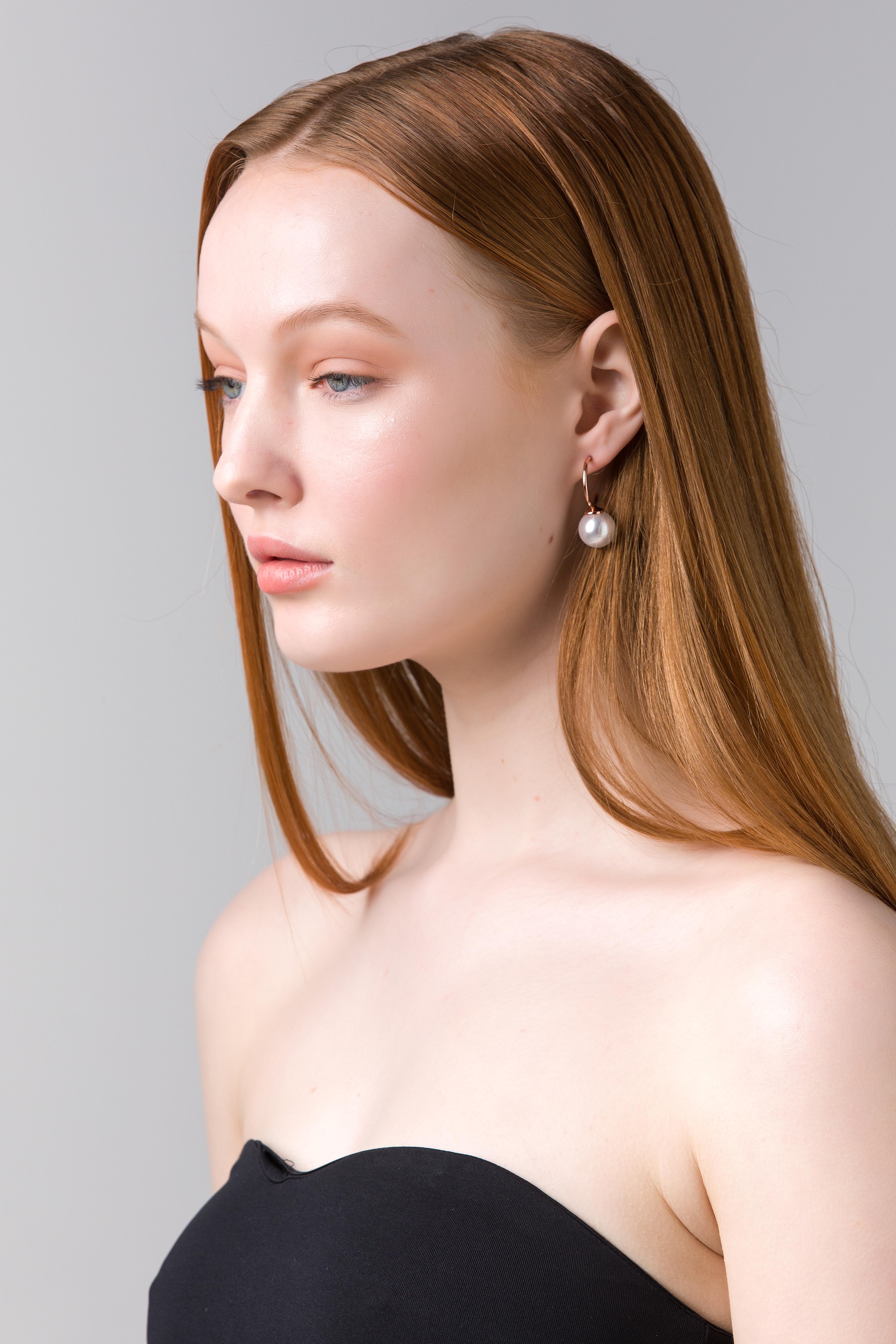 Model with long red hair wearing a gold Kora pearl drop earring.