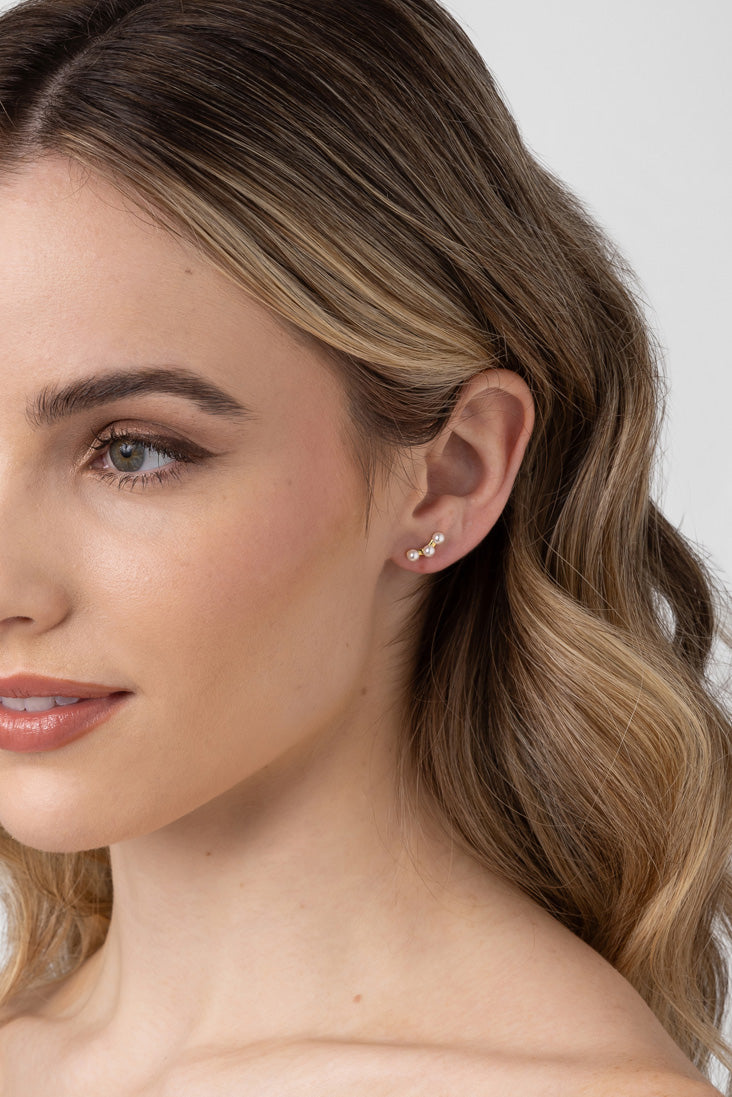 Model wearing the Poppy gold pearl climber, hair swept to one side.