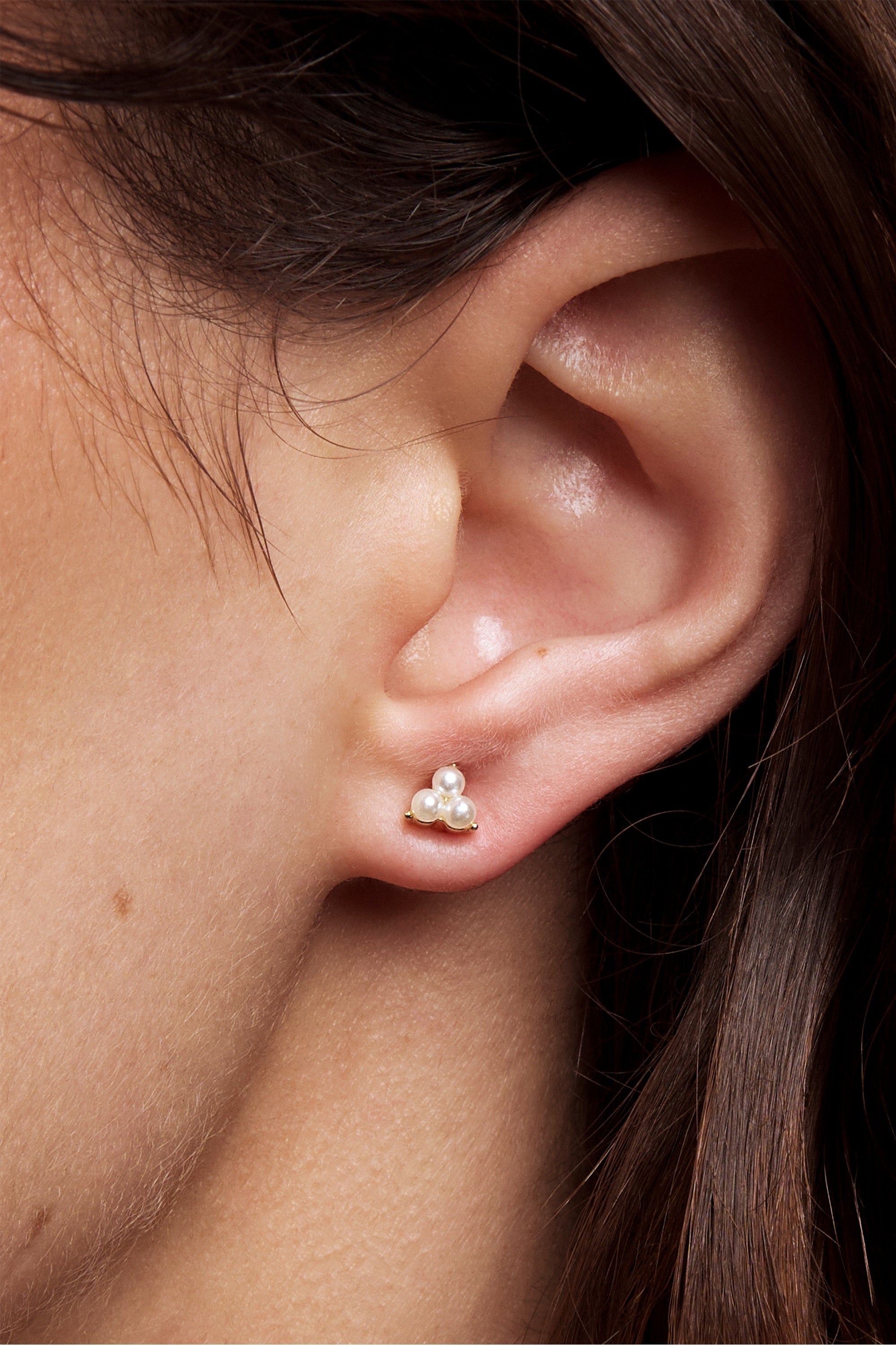 Close-up of a model's ear wearing the Petite Anya silver pearl trio stud.