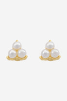 Gold stud earrings, each a small trio of white pearls.