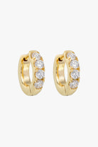 Gold huggie hoops set with a row of four small clear crystals.