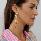 A model in a pink gingham shirt wearing the pearl and multicoloured charm cluster earring.