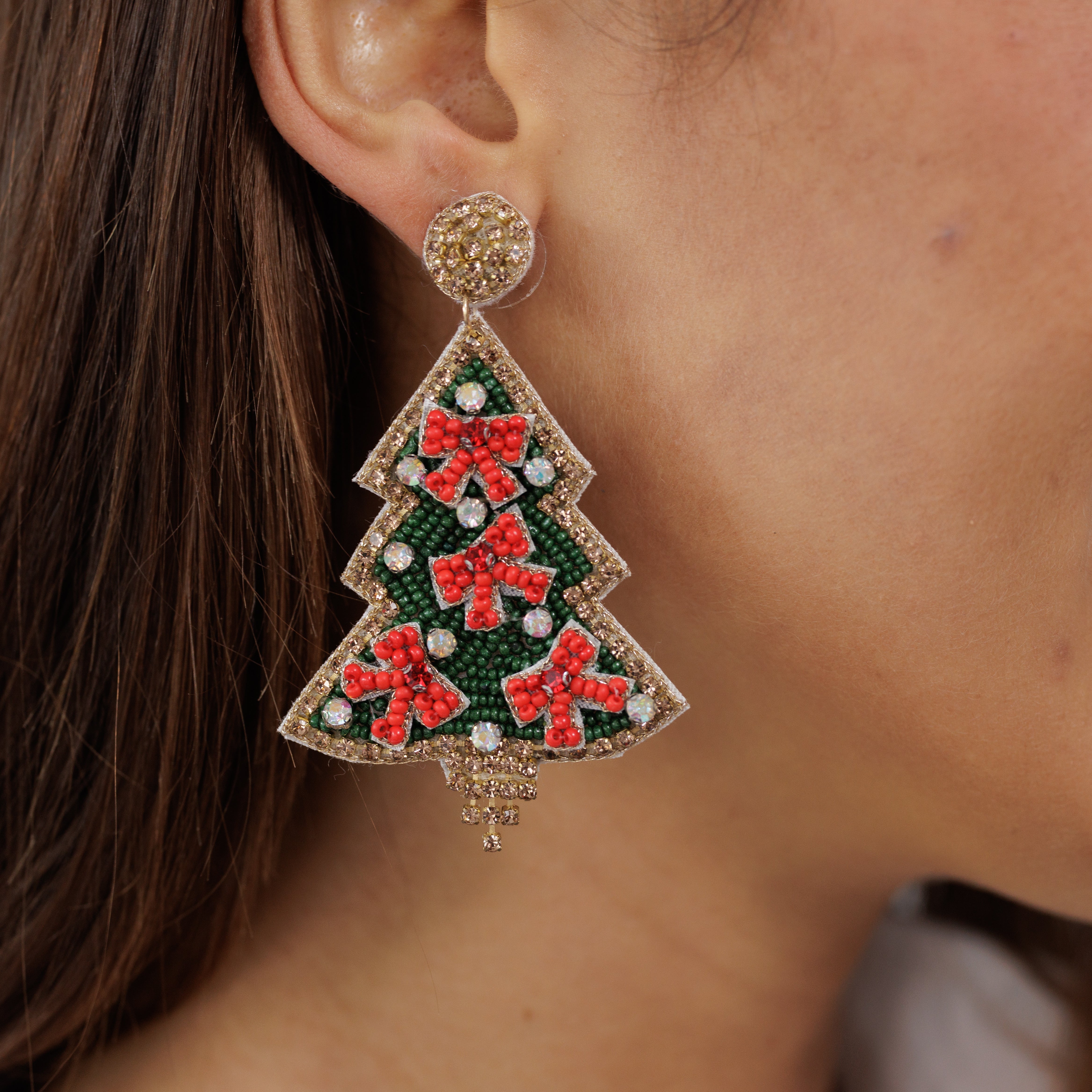 A model wearing the beaded Christmas tree earring, seen in profile.