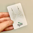 A hand holding the pair of Kindness earrings on a white presentation card