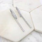 Pair of silver-tone baguette crystal hoop-and-drop earrings on a marble tile