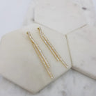Pair of gold-tone double baguette crystal drop earrings on white marble