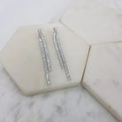 Pair of silver-tone double baguette crystal drop earrings on white marble