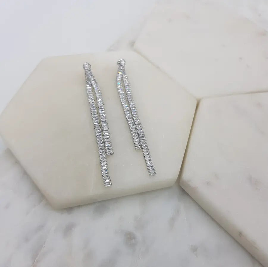 Pair of silver-tone double baguette crystal drop earrings on white marble