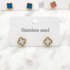White clover stud earrings on a card, with teal and pink pairs behind, on marble
