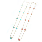 Two gold-tone clover station necklaces, one with teal clovers and one with pink clovers, on white