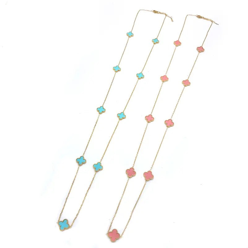 Two gold-tone clover station necklaces, one with teal clovers and one with pink clovers, on white